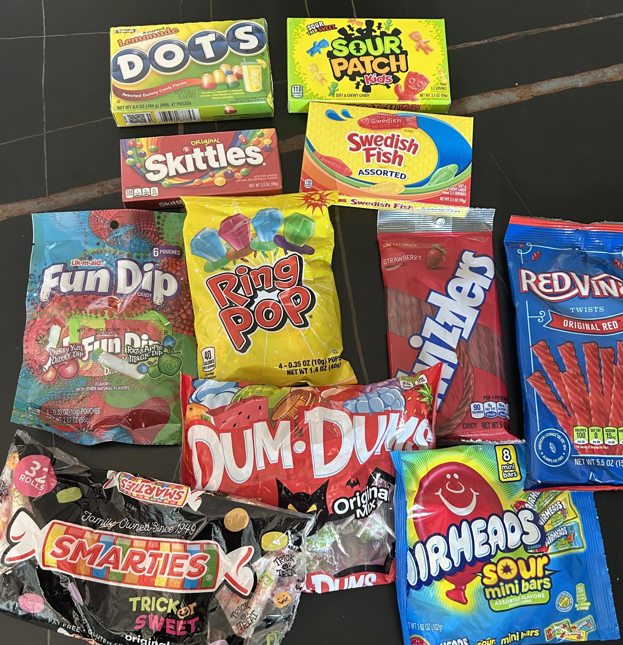Assortment of Halloween candy including Fun Dip, Dum Dums, Smarties, Airheads, Twizzlers, Red Vines and Swedish Fish.