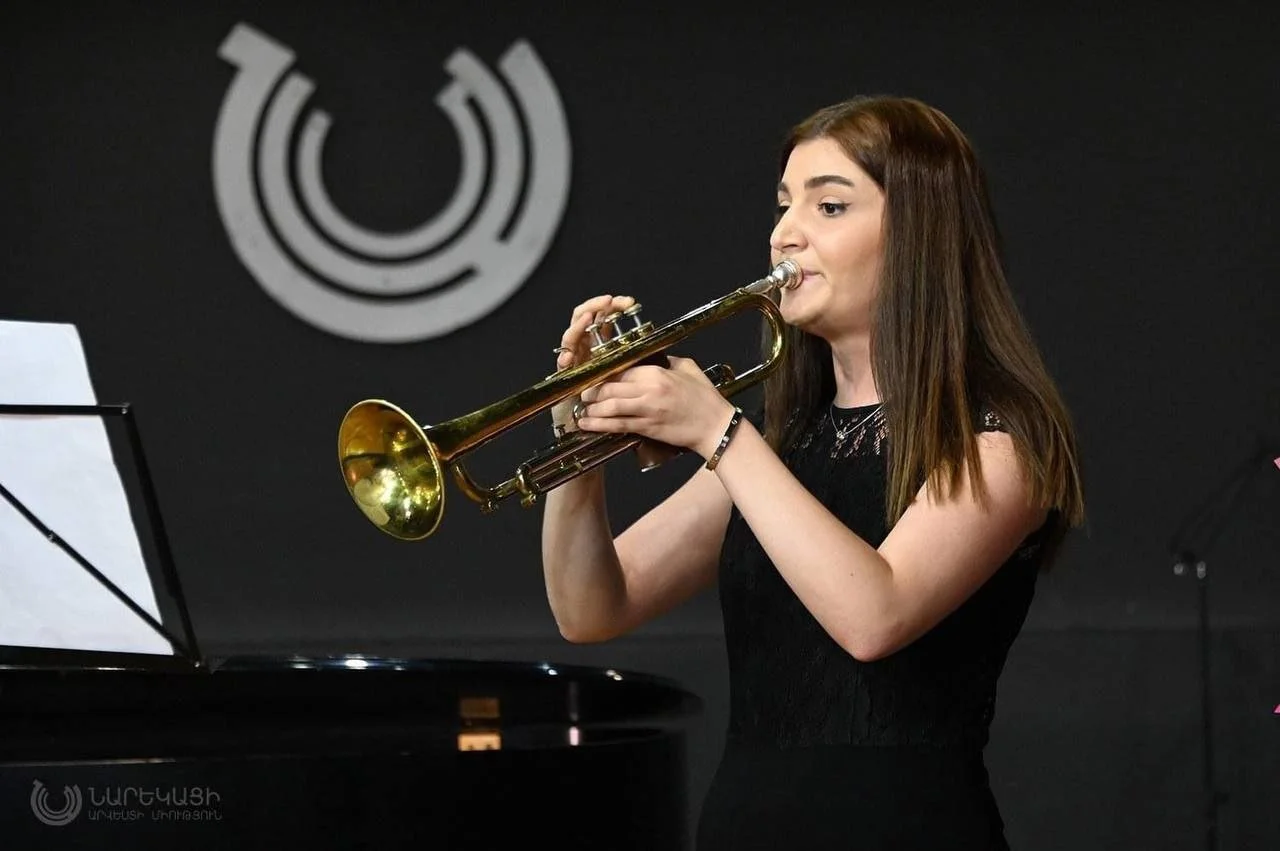 A young woman playing a trumpet in a music performance.