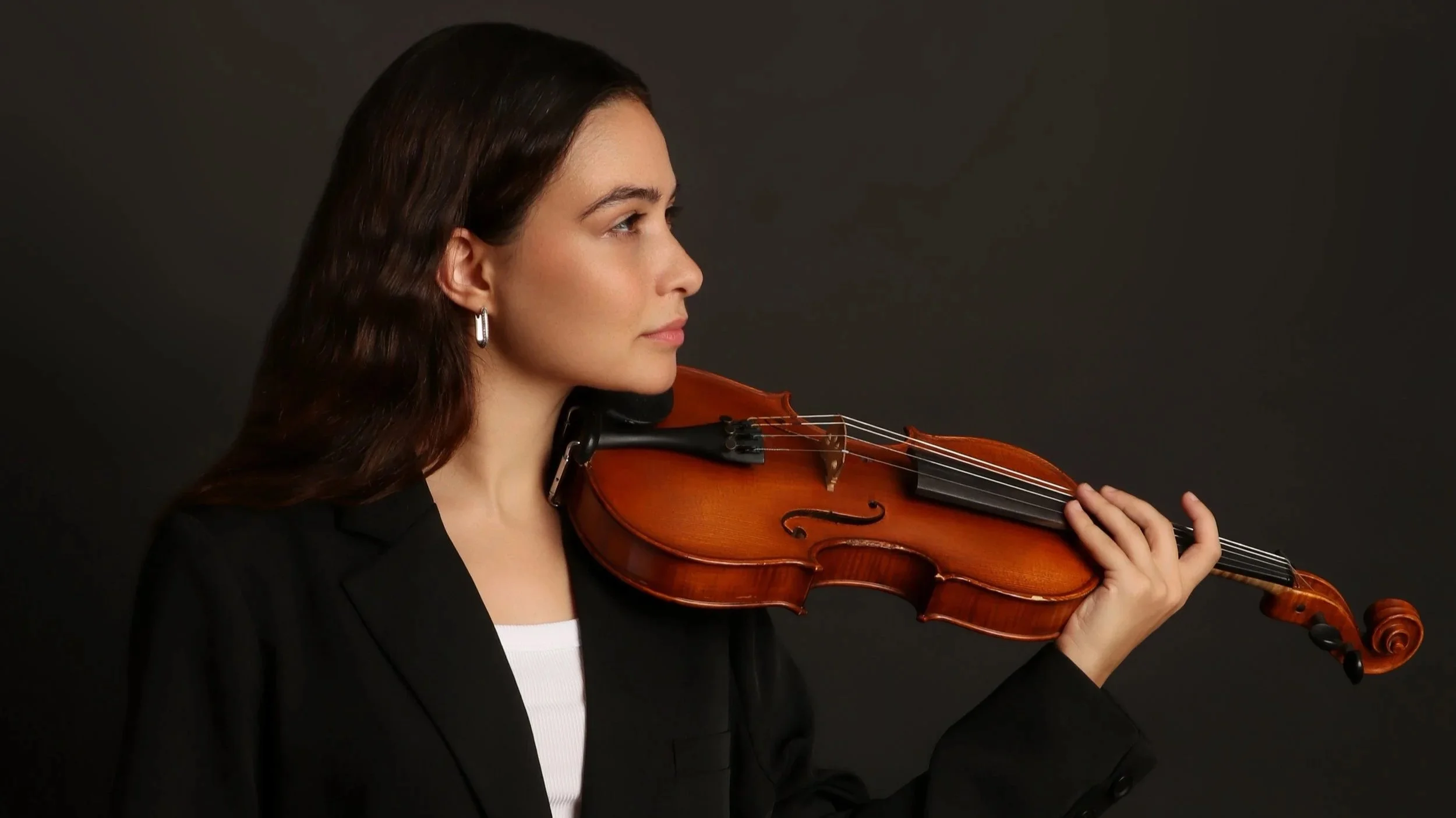 Woman playing a violin against a dark background