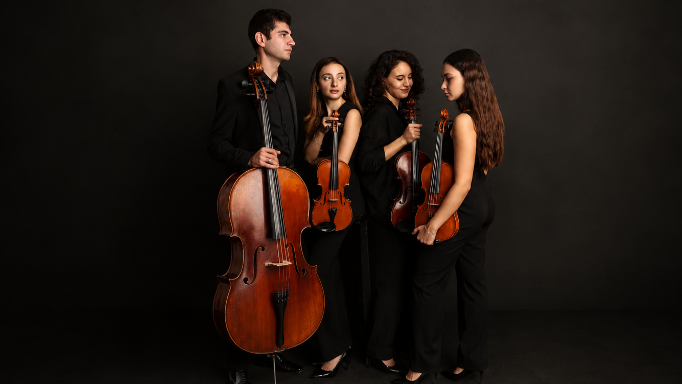 Four musicians dressed in black holding string instruments, standing against a black background.