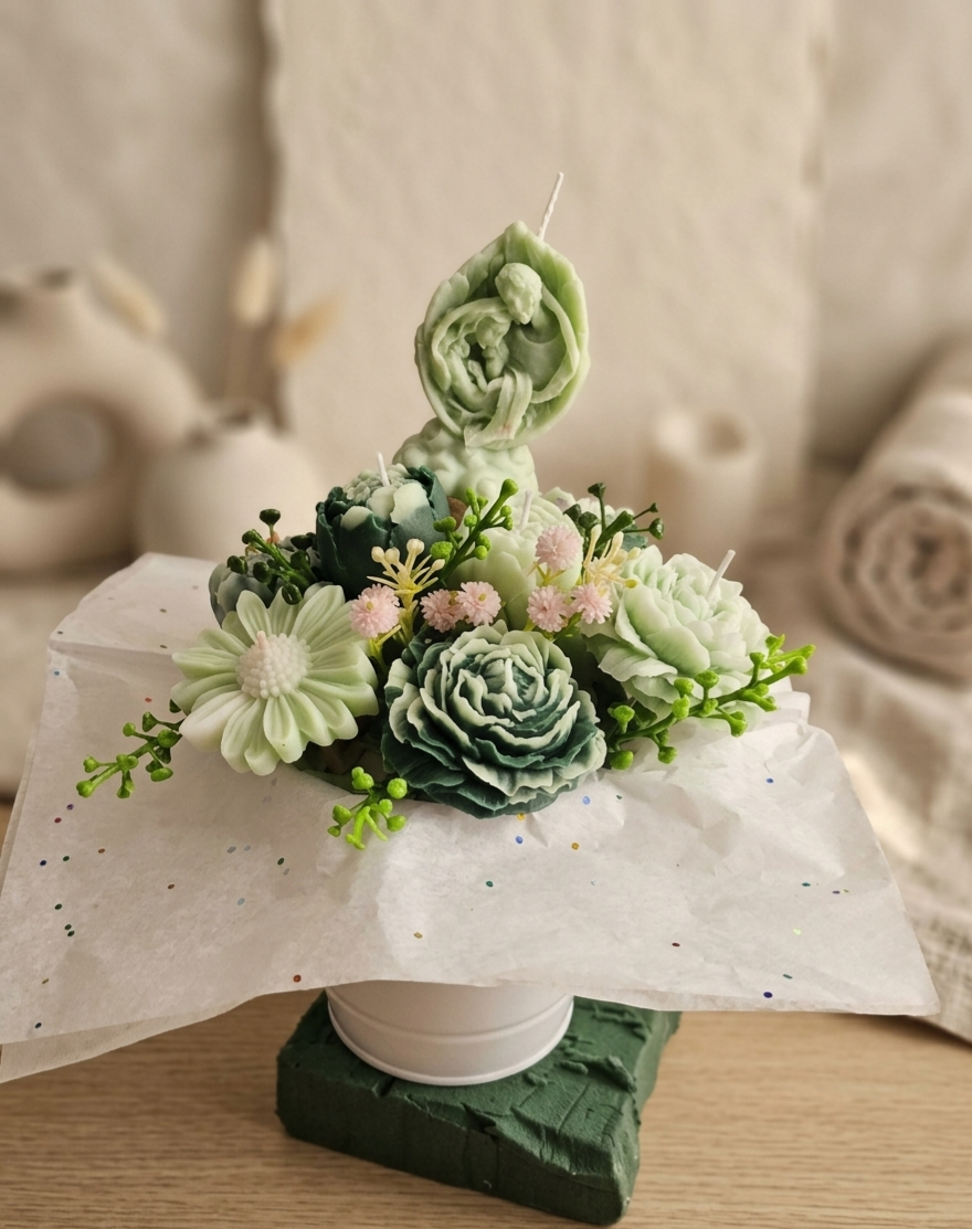 Un arreglo decorativo con velas en forma de flores y hojas, en una base blanca y rodeado de papel decorativo, sobre una superficie de madera.