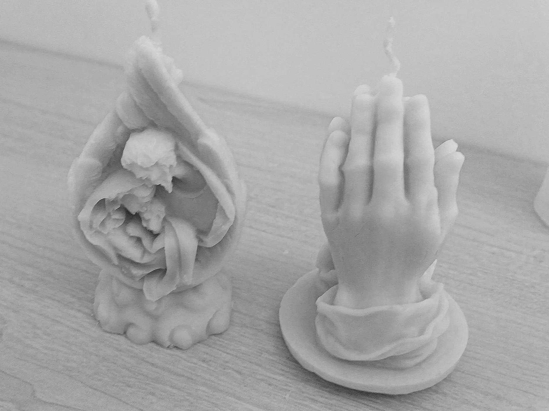 Mano haciendo una señal de paz junto a una flor en una mesa de madera.