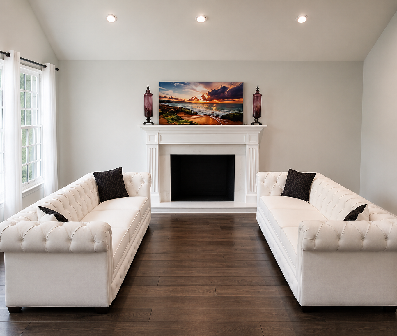 Living room with two white tufted sofas facing each other, a white fireplace with a landscape painting above it, and dark hardwood flooring.