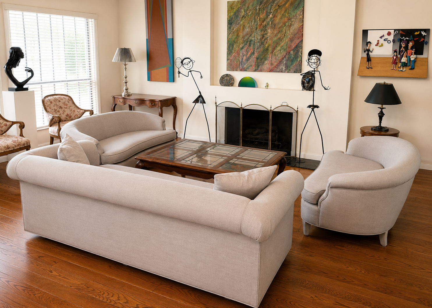 Living room with beige sofas and armchair, wooden coffee table, and wall art, decorative sculptures, and lamps.