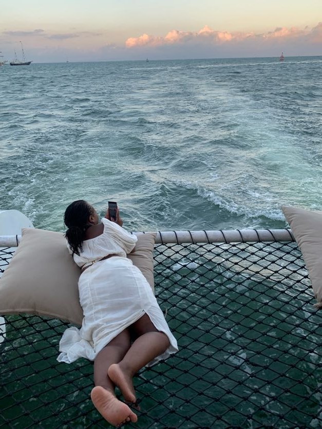 Guest relaxing on a private catamaran boat party at sunset during the Blessed In Bali experience by After Sunday