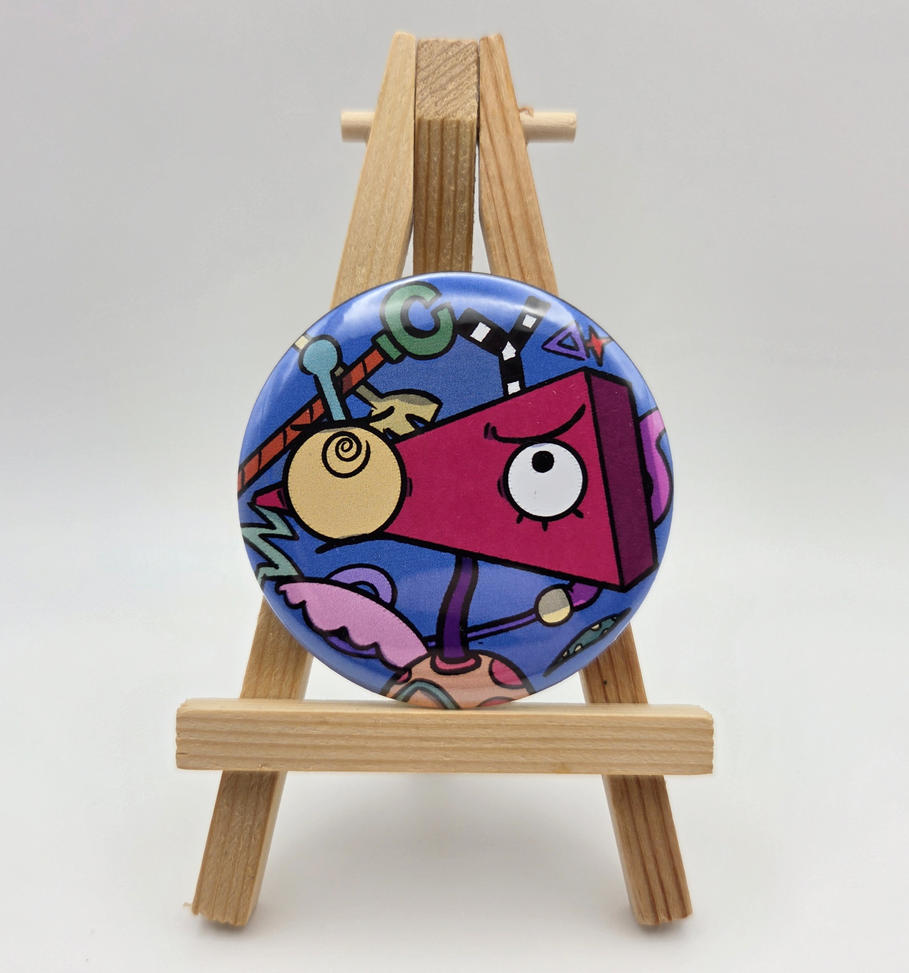 A button featuring ZOOBLE from THE AMAZING DIGITAL CIRCUS resting on a small easel.