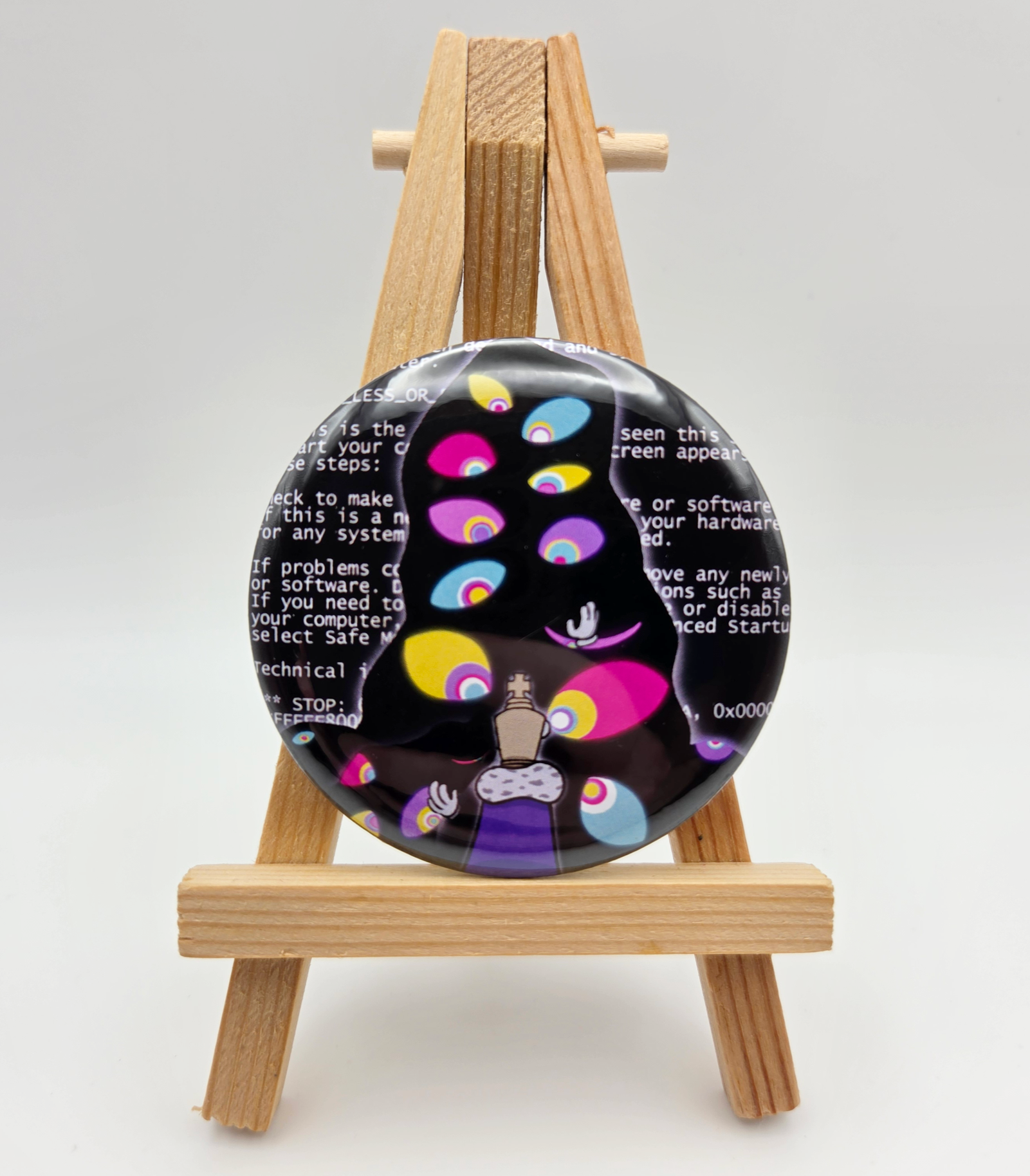 A button featuring KINGER from THE AMAZING DIGITAL CIRCUS resting on a small easel.