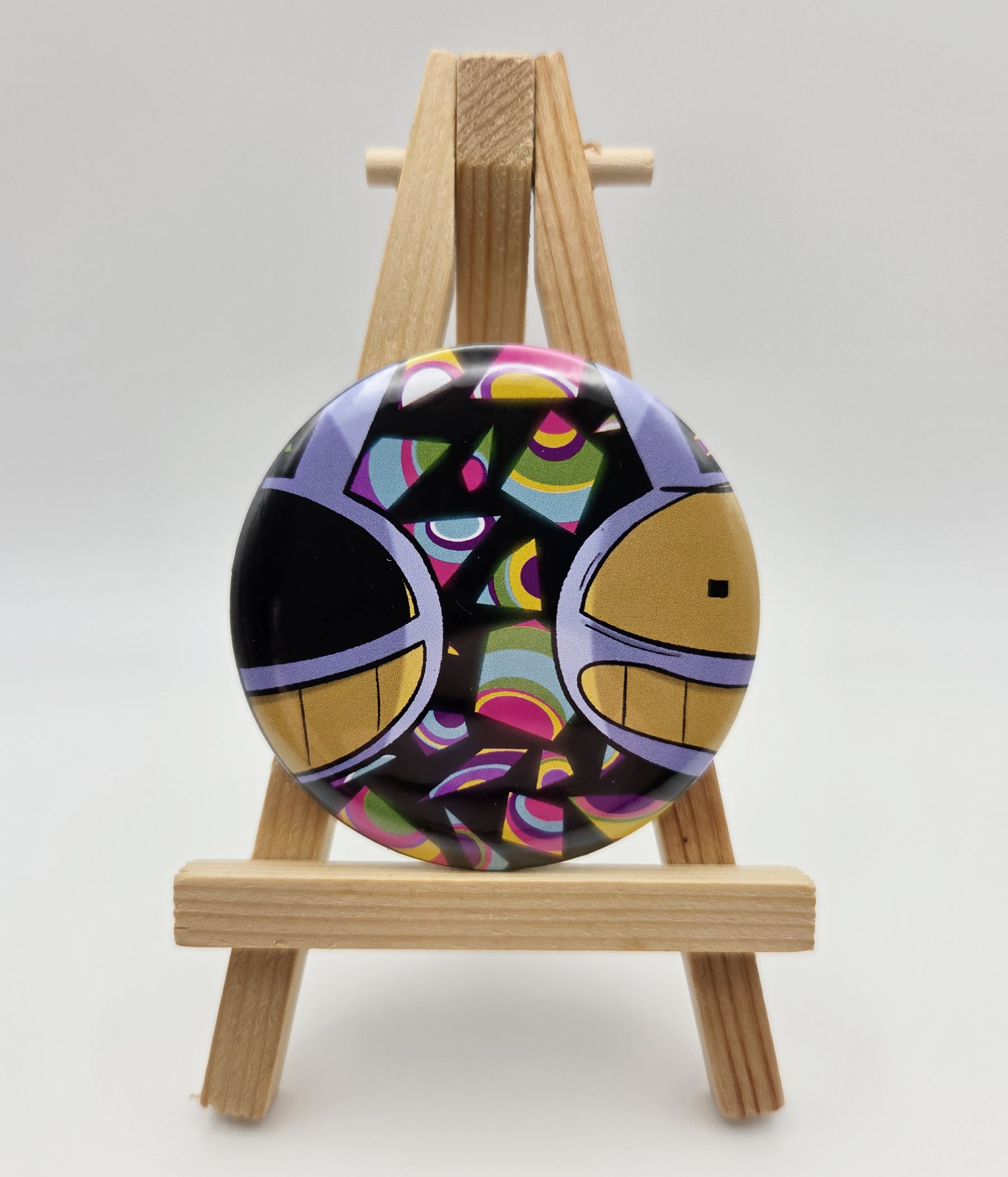 A button featuring JAX from THE AMAZING DIGITAL CIRCUS resting on a small easel.
