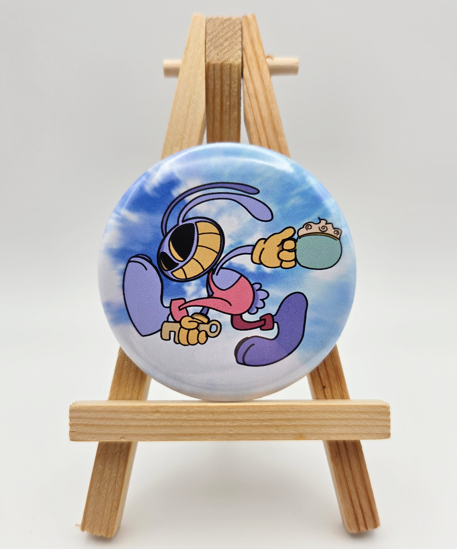 A button featuring JAX from THE AMAZING DIGITAL CIRCUS resting on a small easel.