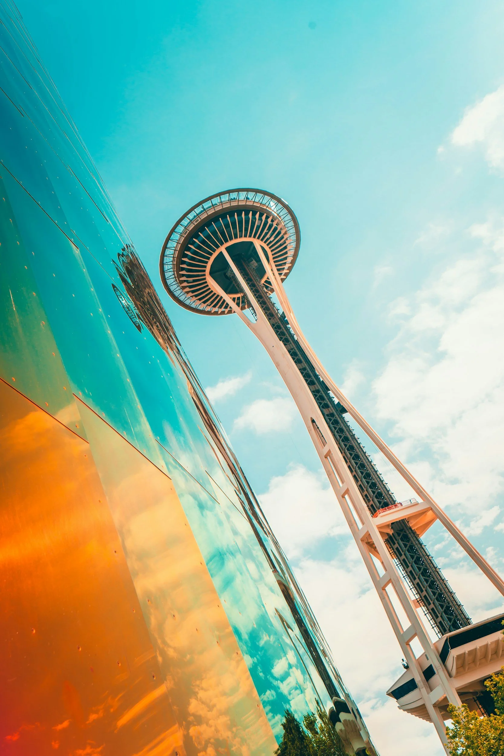 A view of the Space Needle in Seattle, Washington, with a reflection of the sky and clouds on the water or a shiny surface in the foreground.