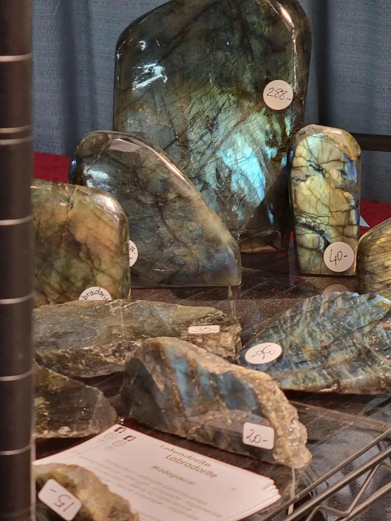 Display of various polished stones with price tags, including labradorite and other mineral specimens in a glass case at a store.