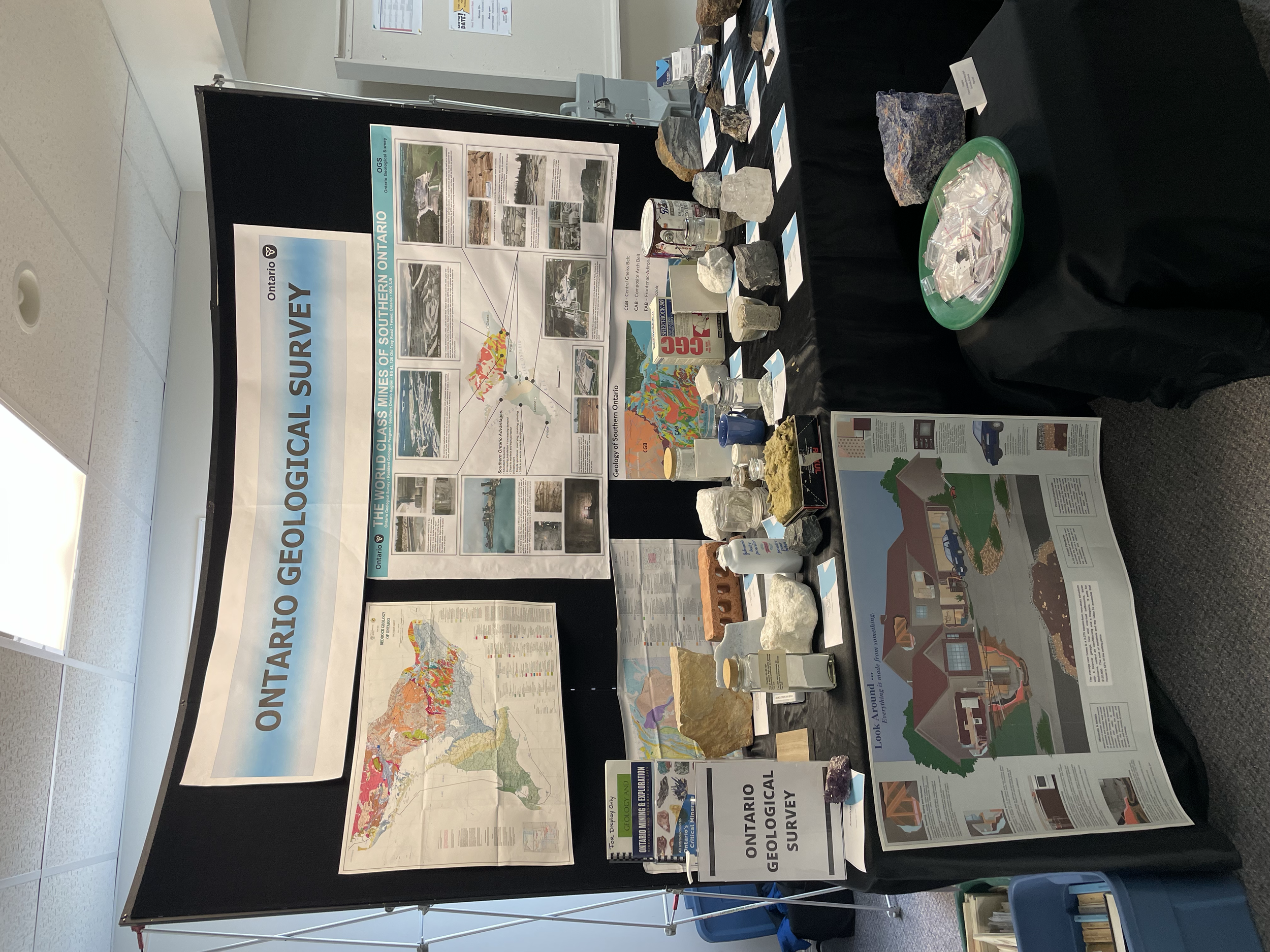An informational display board for a geology survey of southeastern Ontario, featuring maps, photographs, and mineral samples related to the geological features and mineral deposits of the region.