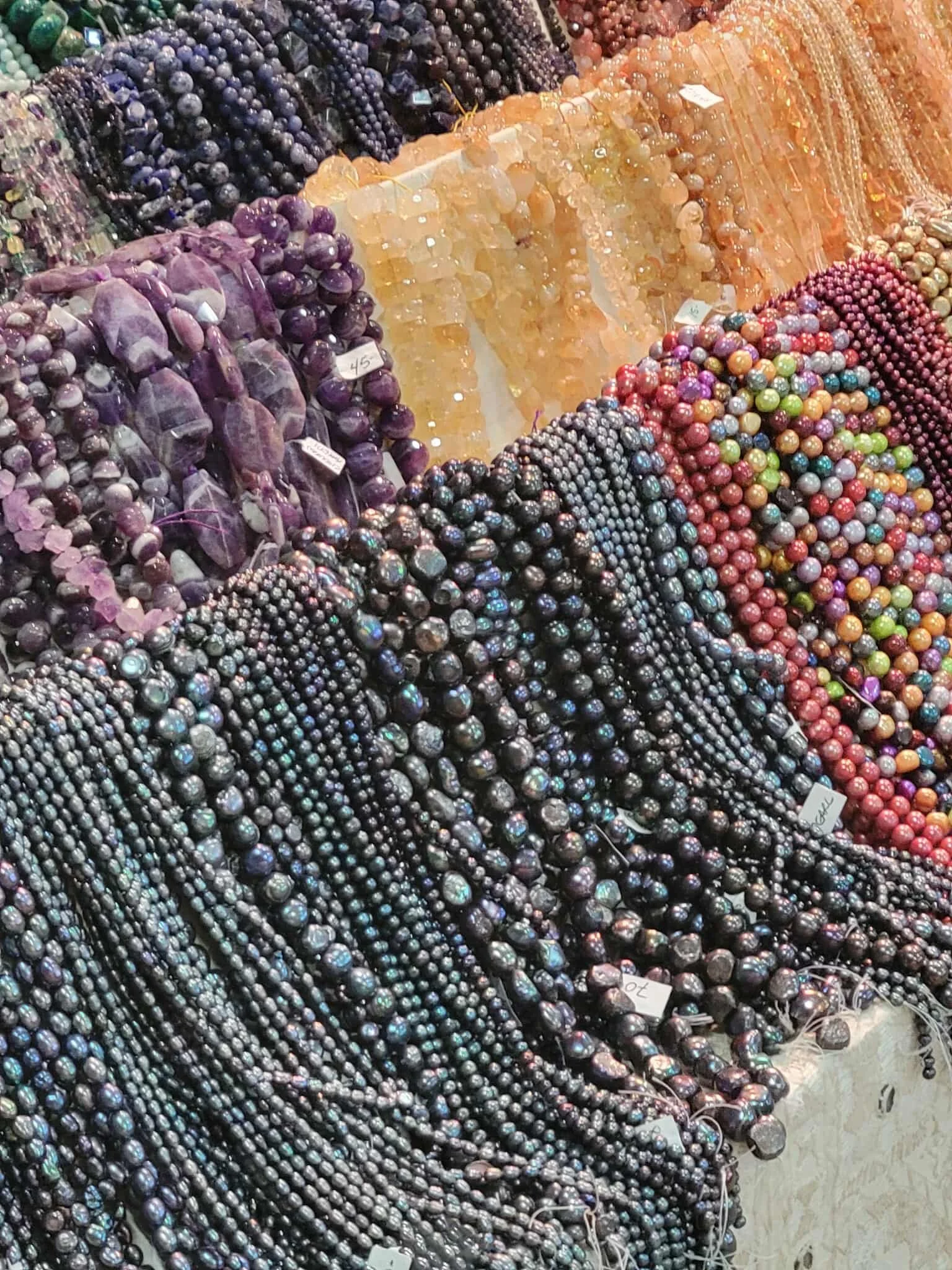 Various colorful beaded necklaces and jewelry displayed on a market stall.