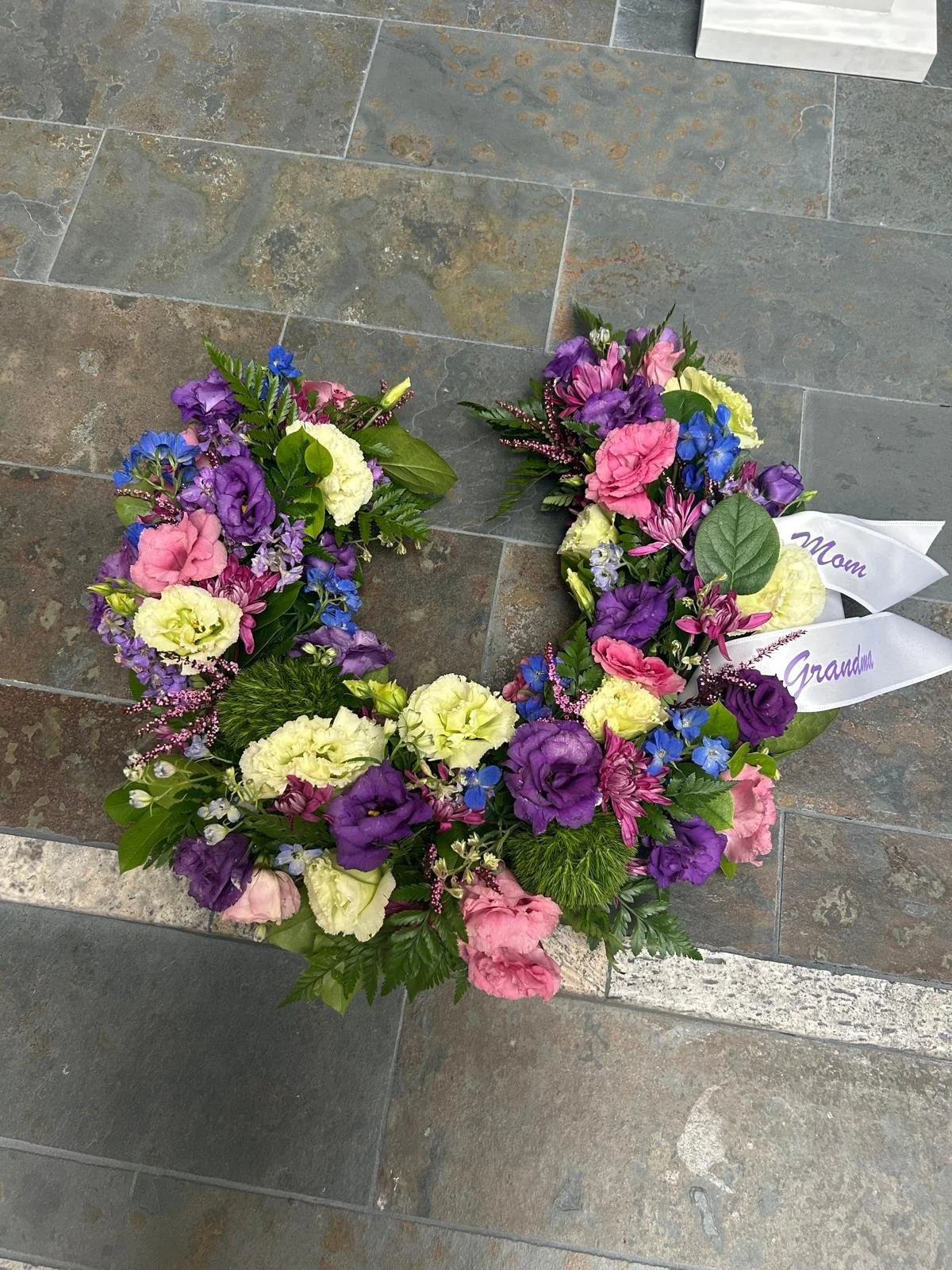 Hanging Horseshoe Spray ft lisianthus and dark blue delphinium.