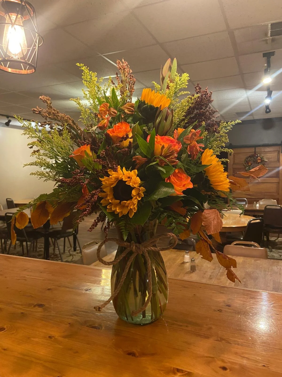 Lg Vase Arrangement ft fall greenery, sunflowers, and free spirit roses.