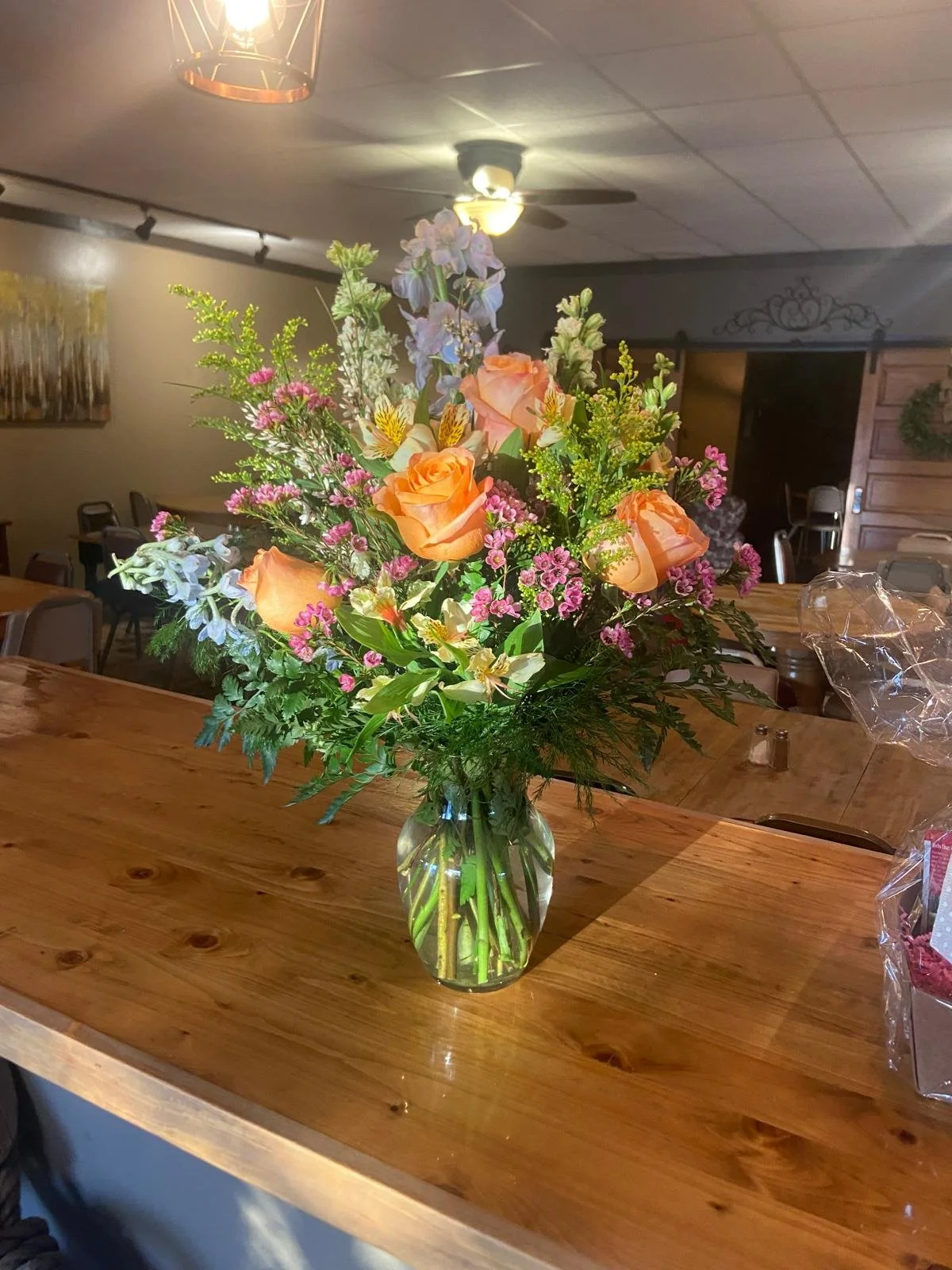 Med Vase Arrangement ft coral roses, and light blue delphinium.