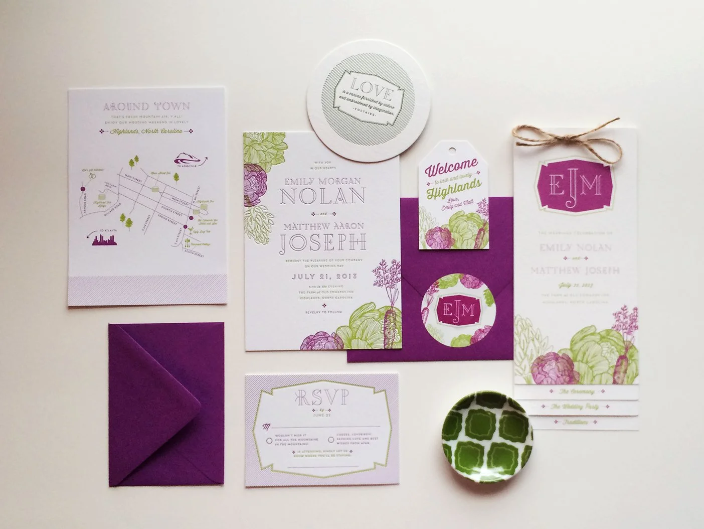 Wedding invitation decor items including a map, RSVP card, thank you notes, monogram sticker, and tags in purple, green, and white colors with floral and map designs.