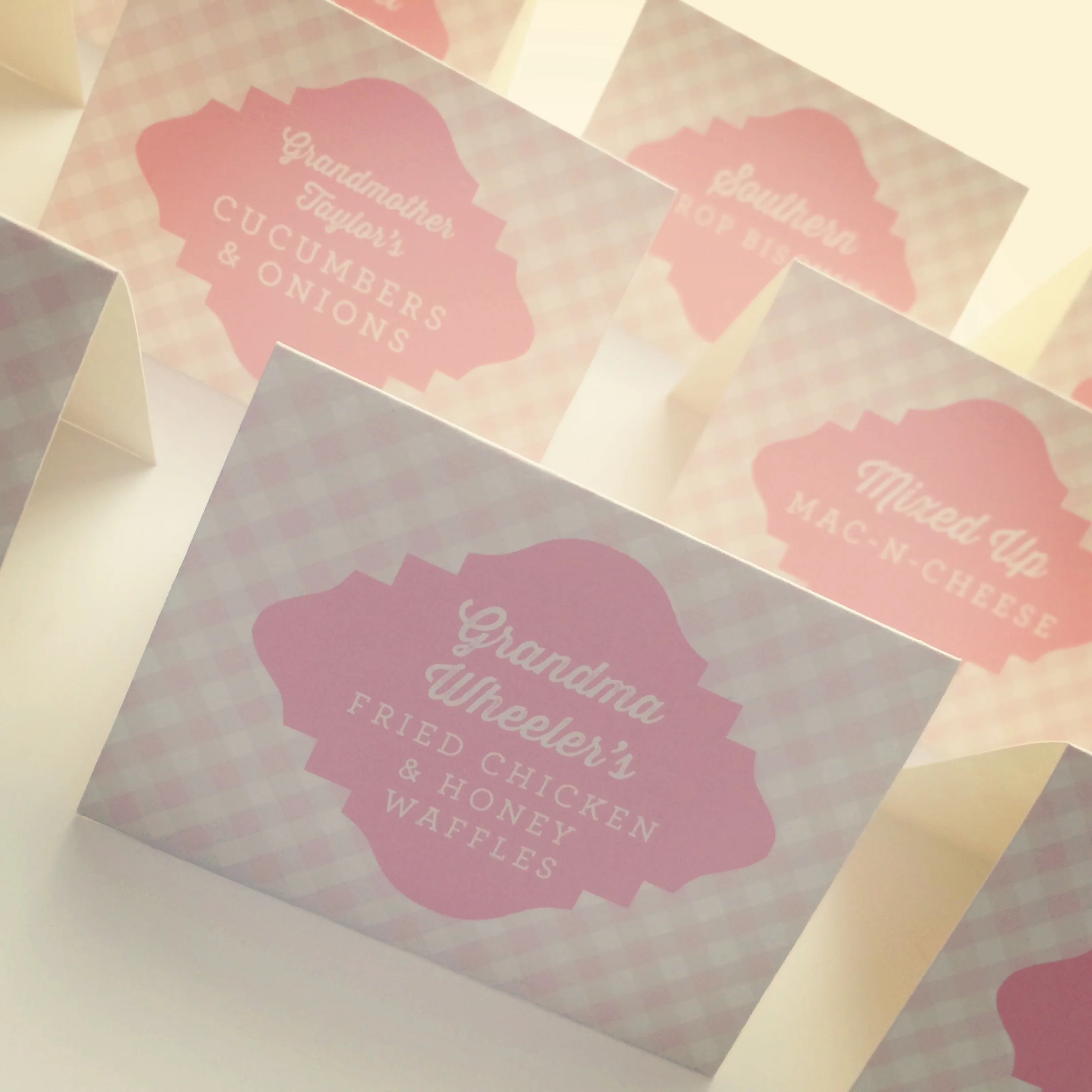 Packaging box with pink label that reads "Grandma Wheeler's Fried Chicken & Honey Waffles," featuring a pink and white checkered pattern.