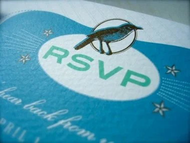 A keychain with a fish pendant hanging over a RSVP event card featuring a blue and white background with starfish and the text 'RSVP' in green.