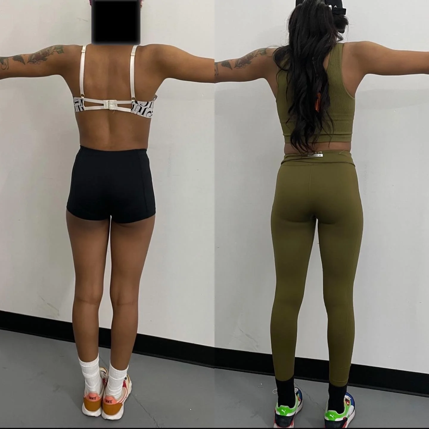 Two women standing with arms outstretched, facing away from the camera in front of a plain white wall. The woman on the left is wearing a white and black sports bra, black shorts, white socks, and orange and white sneakers. The woman on the right is 