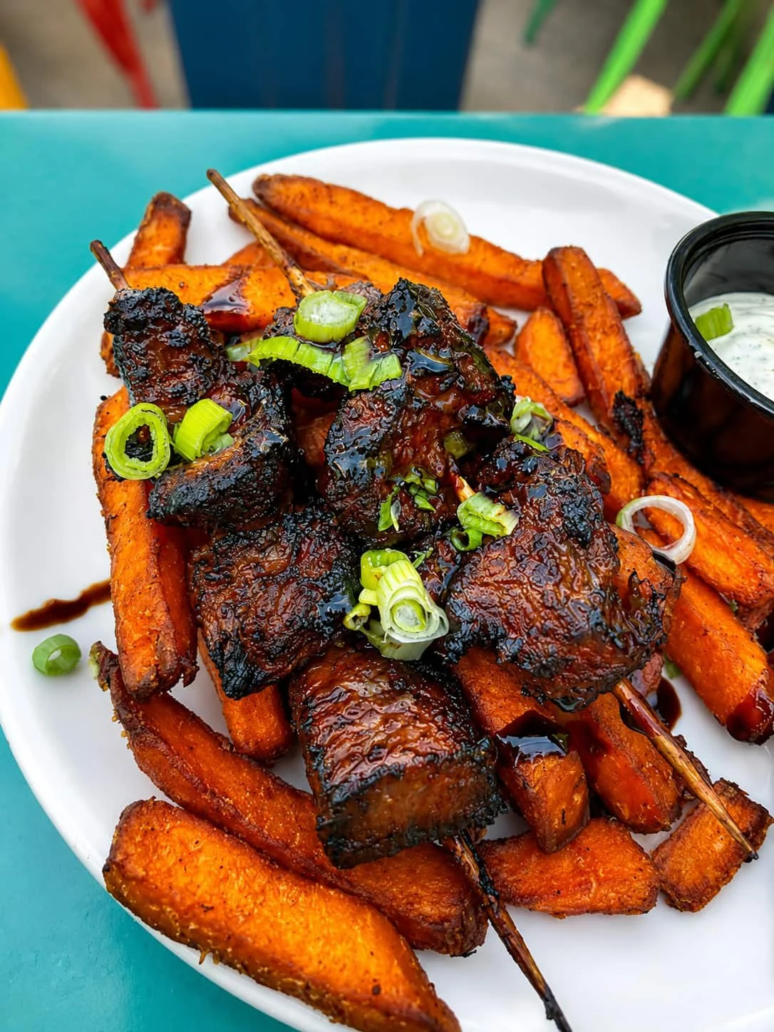 Asian beef skewers with green onion garnish and sweet potato fries at Tapas & Tacos Beer Garden in Lake Leelanau, Michigan