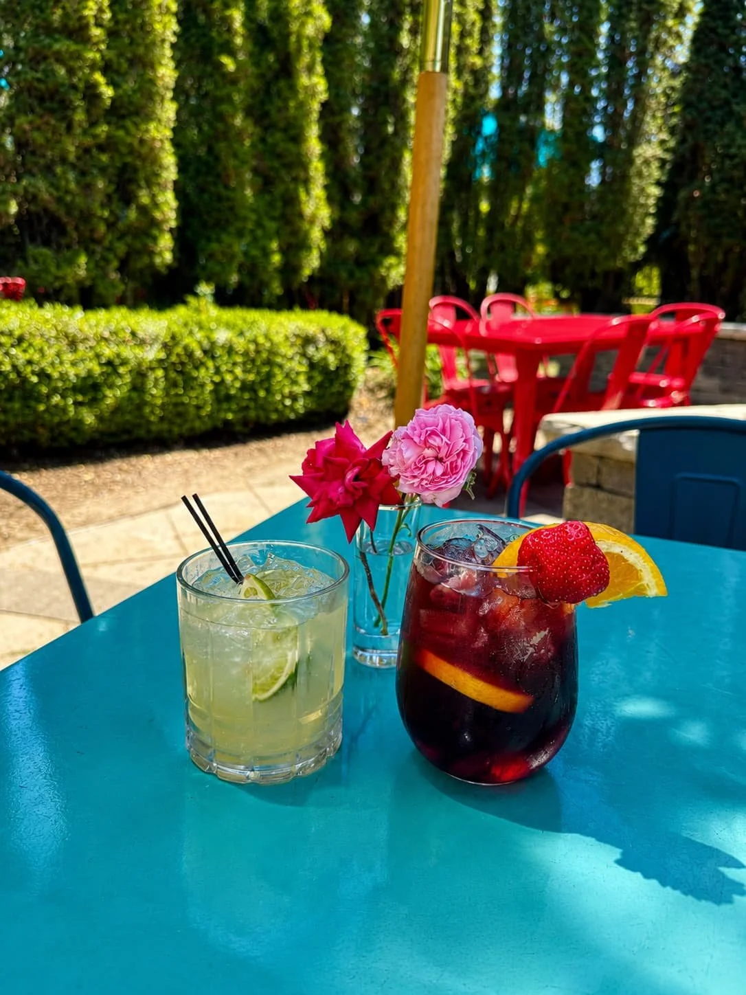 Two colorful cocktails with margarita and sangria on blue patio table with fresh flowers at Tapas & Tacos Beer Garden in Lake Leelanau, Michigan