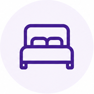 A simple, purple line drawing of a bed with pillows on top, set against a white circular background.