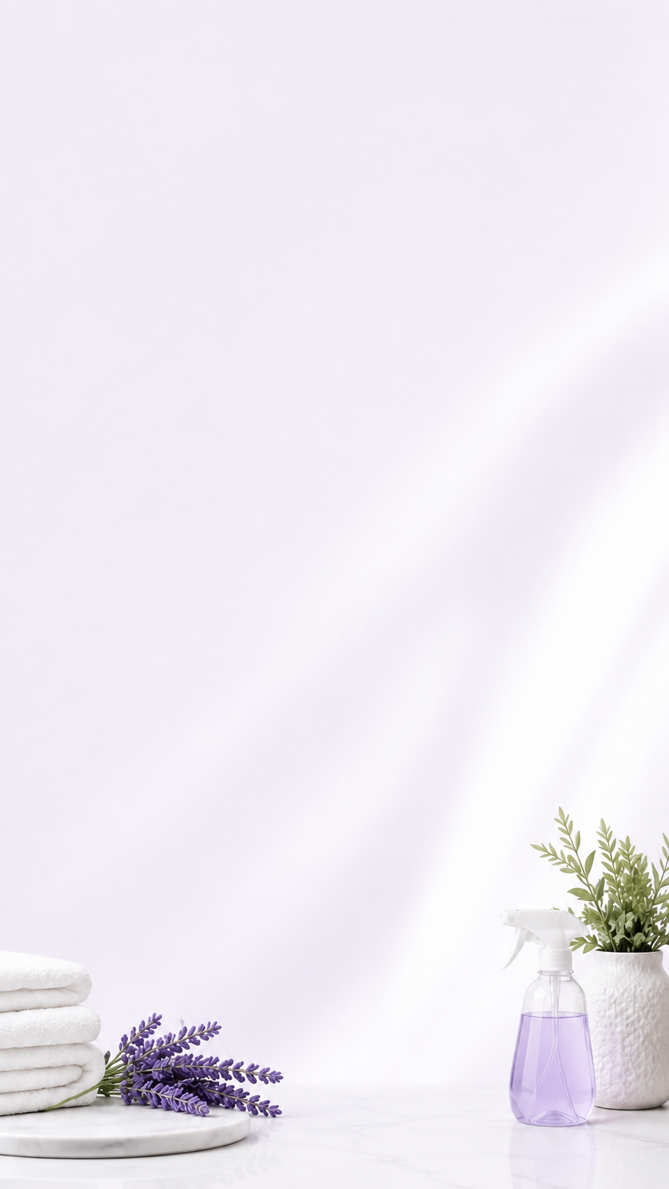 A clean white surface with folded white towels, a sprig of lavender, a spray bottle with purple liquid, and a white potted plant with green foliage on a white background.