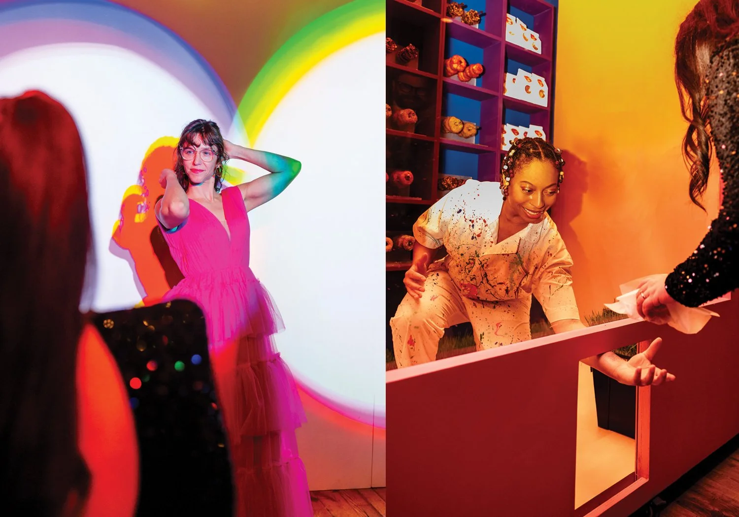 A gala guest in a hot pink dress poses in front of a vibrant rainbow light installation while being photographed, alongside a performer in a paint-splattered white costume engaging guests at an interactive food station.