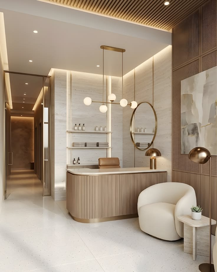 A modern reception area with a curved wooden counter, a round mirror, a white armchair, a small table with a succulent, and contemporary lighting fixtures in a neutral-toned interior.