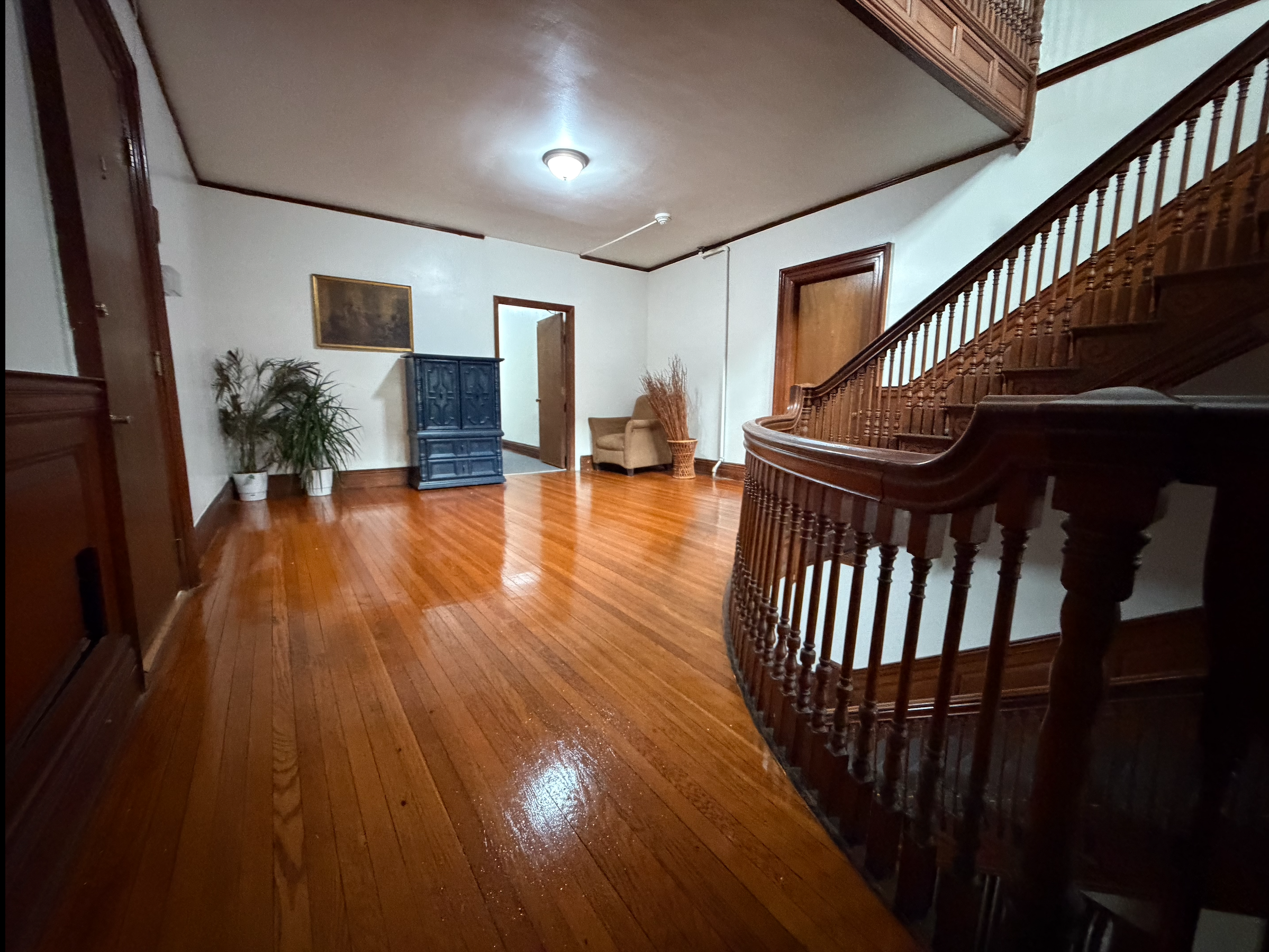 Interior view of a wooden staircase and hardwood flooring in a well-lit house.