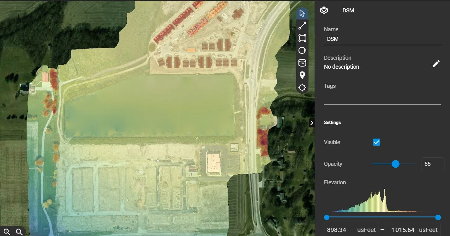 Aerial view of a construction site digital surface map (DSM) with a large field at the center, surrounded by roads, buildings, and patches of trees, with a digital interface overlay on the right showing map settings.