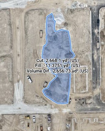 Aerial view of a construction site with a blue outline showing a stockpile of dirt's shape, including volume measurements for fill and cut.