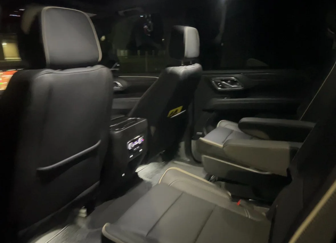 Interior of a GMC Yukon showing the back seats from the front passenger side at night.