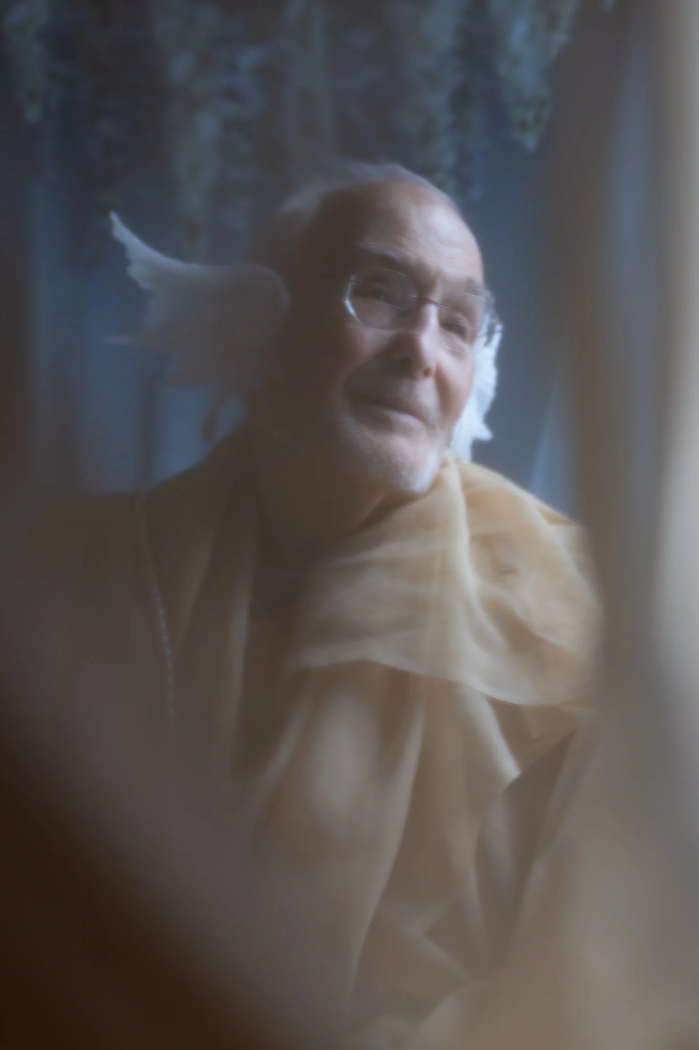 	
An elderly man with glasses and fabric draped around him, dressed like a mermaid