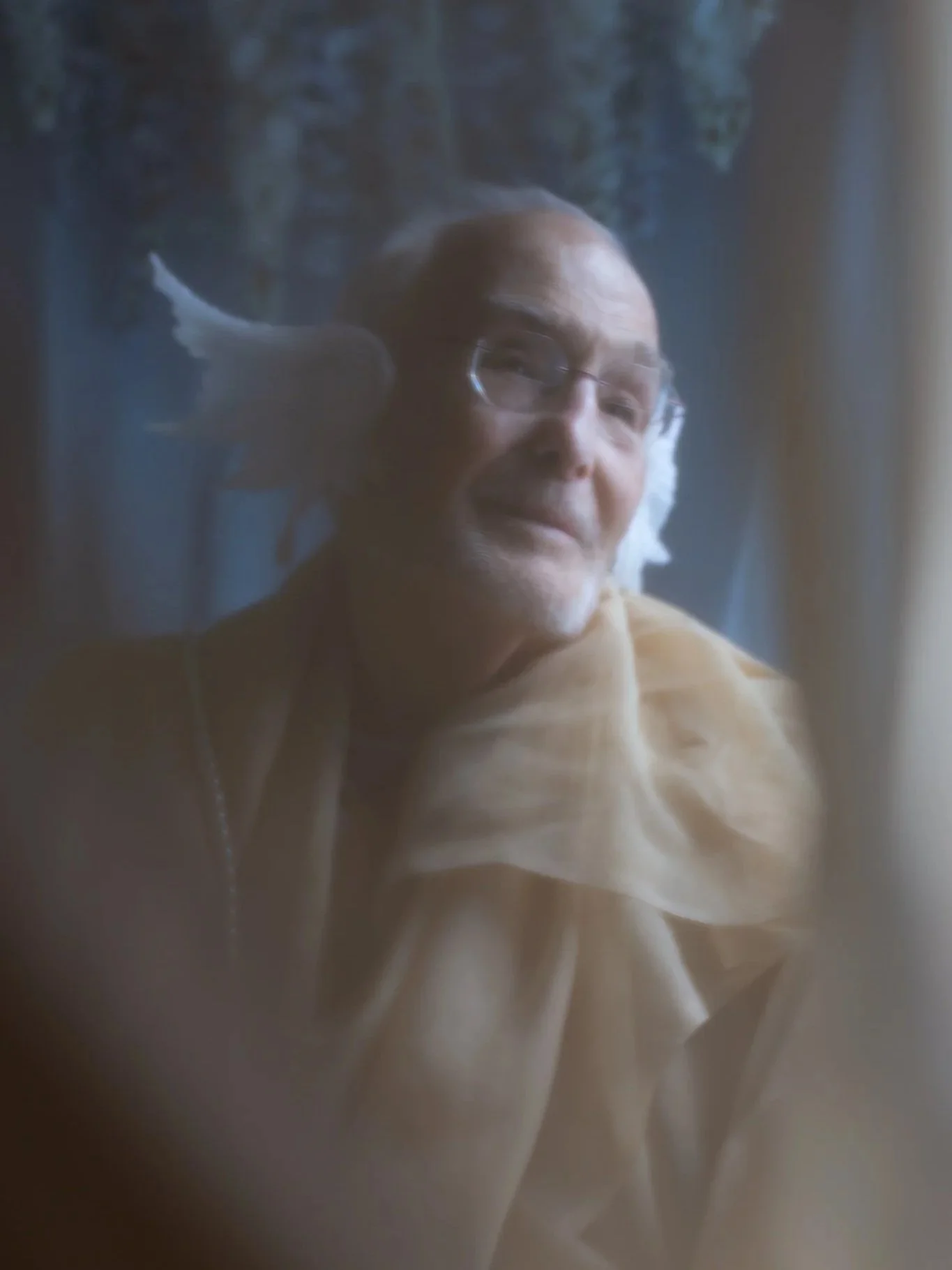 An elderly man with glasses and fabric draped around him, dressed like a mermaid
