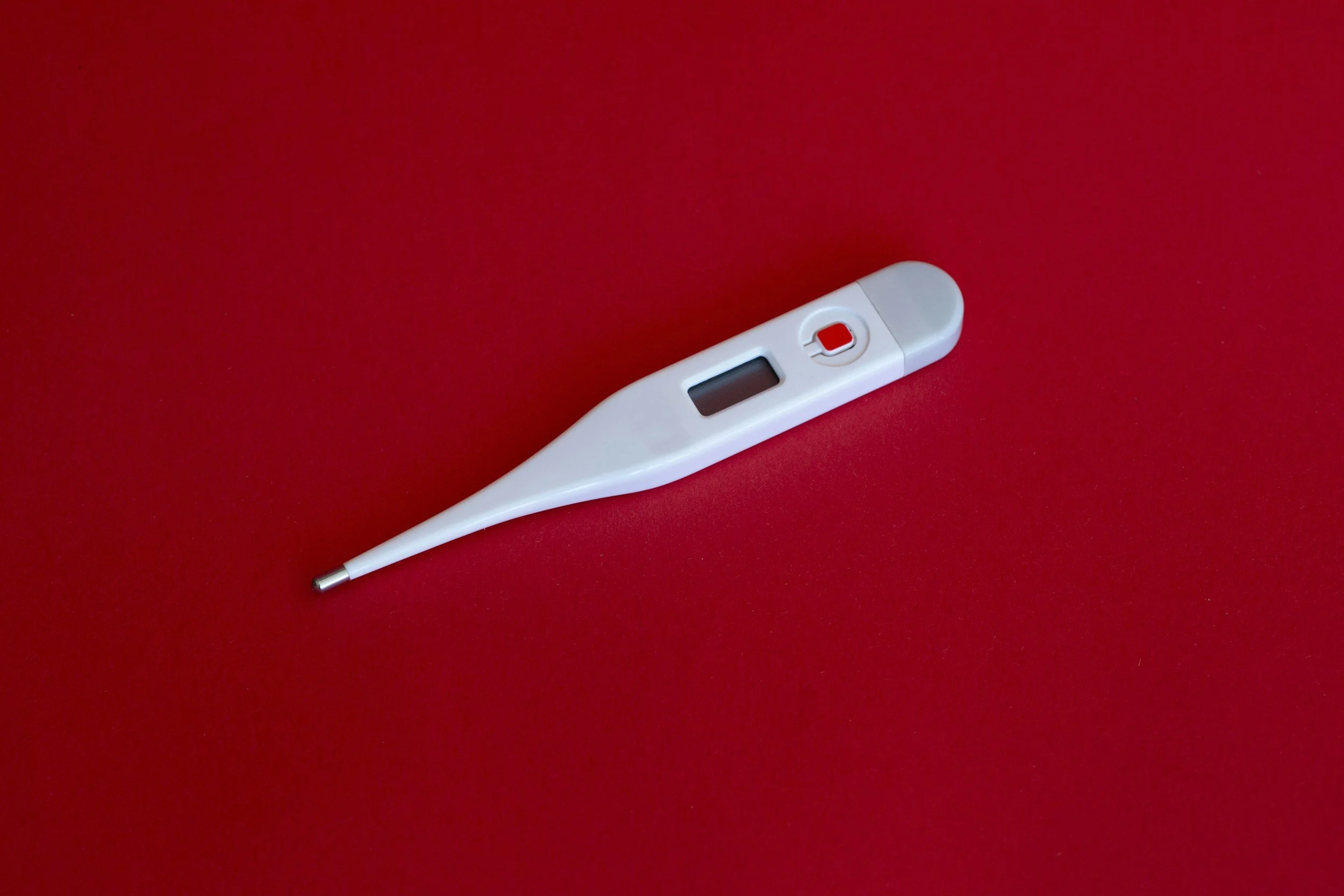 white digital thermometer on a red background