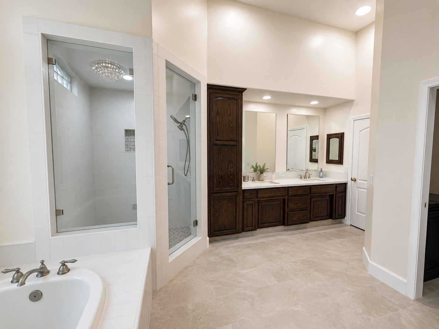 A spacious bathroom featuring a walk-in shower with glass doors, a large white bathtub, a double vanity with dark wood cabinets and two mirrors, and a neutral tile floor.
