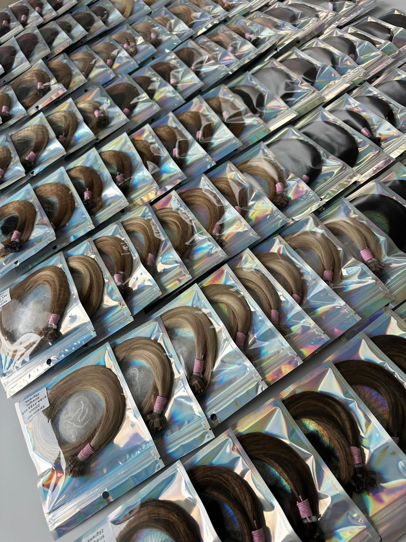 Various packs of hair extensions with pink elastic bands, arranged on a flat surface.