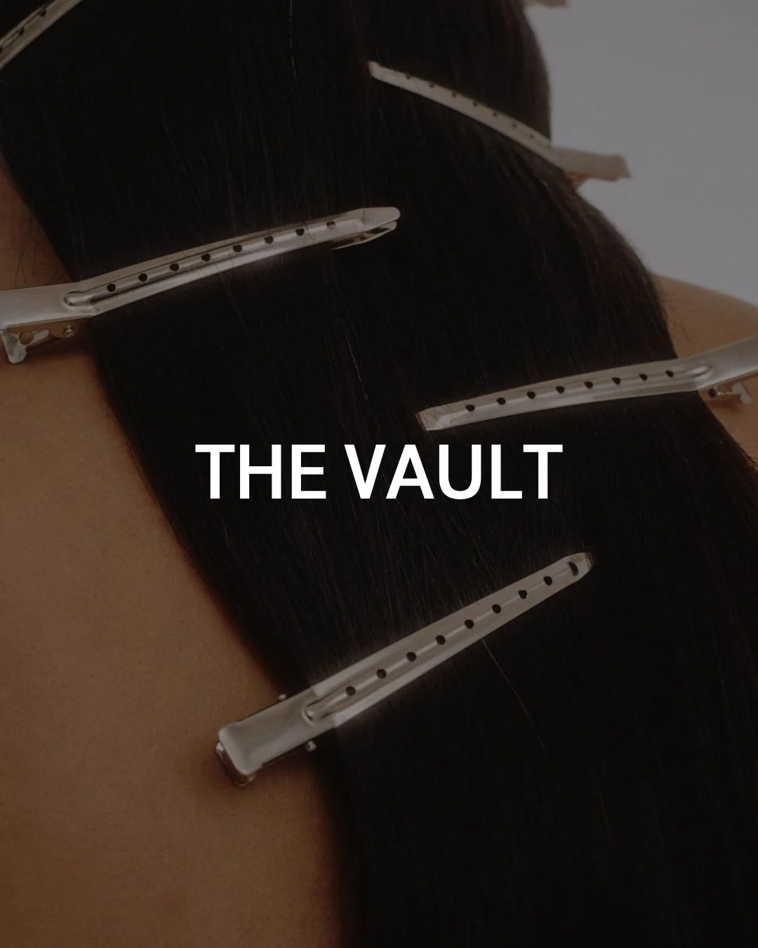 Close-up of a person's scalp with hair extensions secured by metal clips.