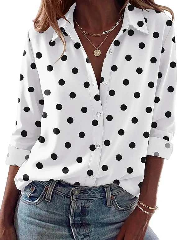 A woman wearing a white button-up shirt with black polka dots, rolled up sleeves, and a pair of denim jeans, accessorized with layered necklaces and gold bracelets.