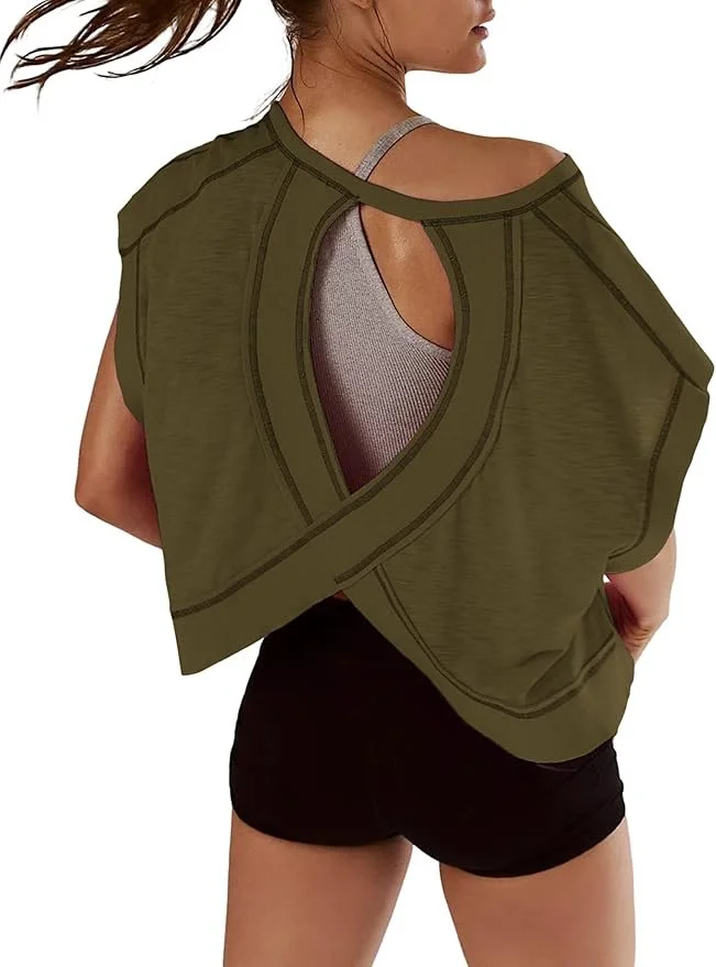 A woman wearing a gray sports bra and black shorts, with an olive green jacket draped over her shoulders, showing an open back design.