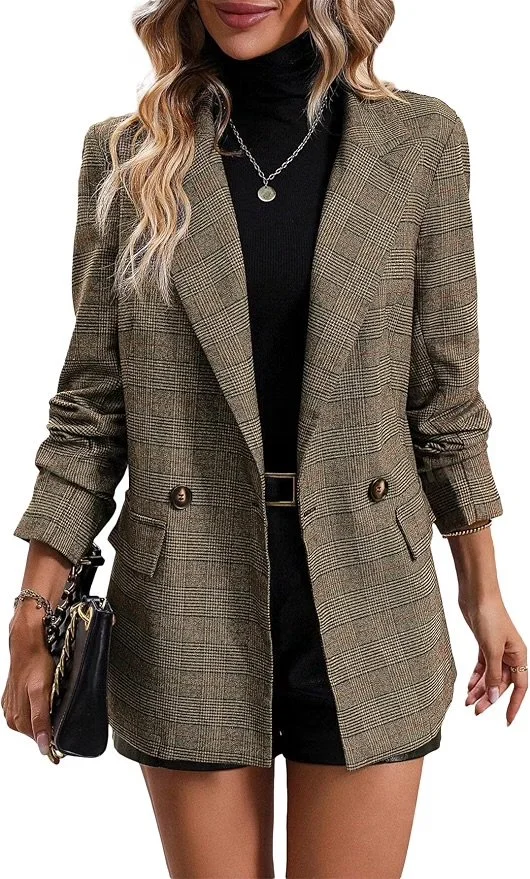 Woman wearing a plaid blazer over a black turtleneck, black shorts, and holding a black handbag with chain details.