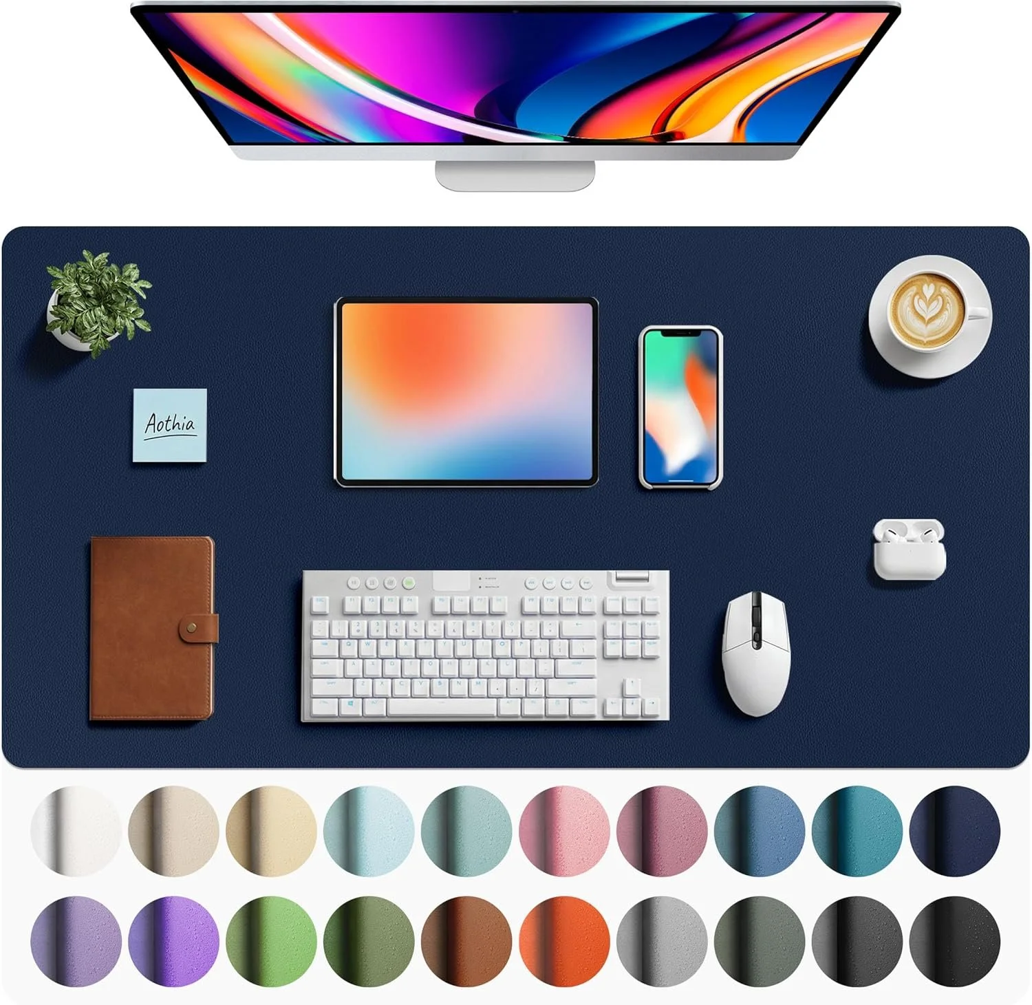 Overhead view of a workspace with a desktop computer, tablet, smartphone, keyboard, mouse, notebook, plant, coffee cup, and AirPods on a dark blue mat, with color swatches below.