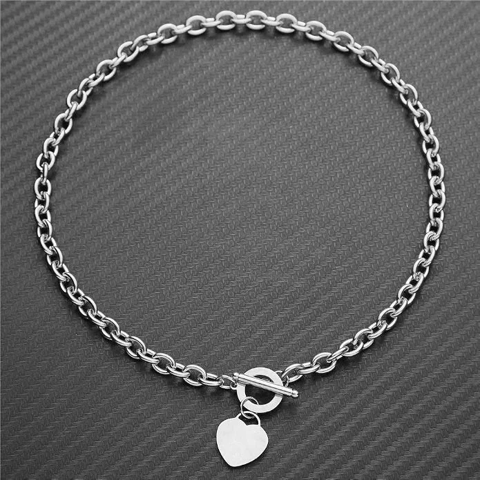 Silver chain necklace with a heart-shaped pendant on a dark textured background.