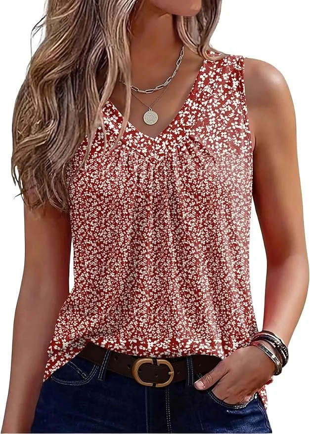 A woman wearing a red sleeveless top with small white floral pattern, dark blue jeans with a brown belt, and layered necklaces. She has long, wavy blonde hair and several bracelets on her right wrist.