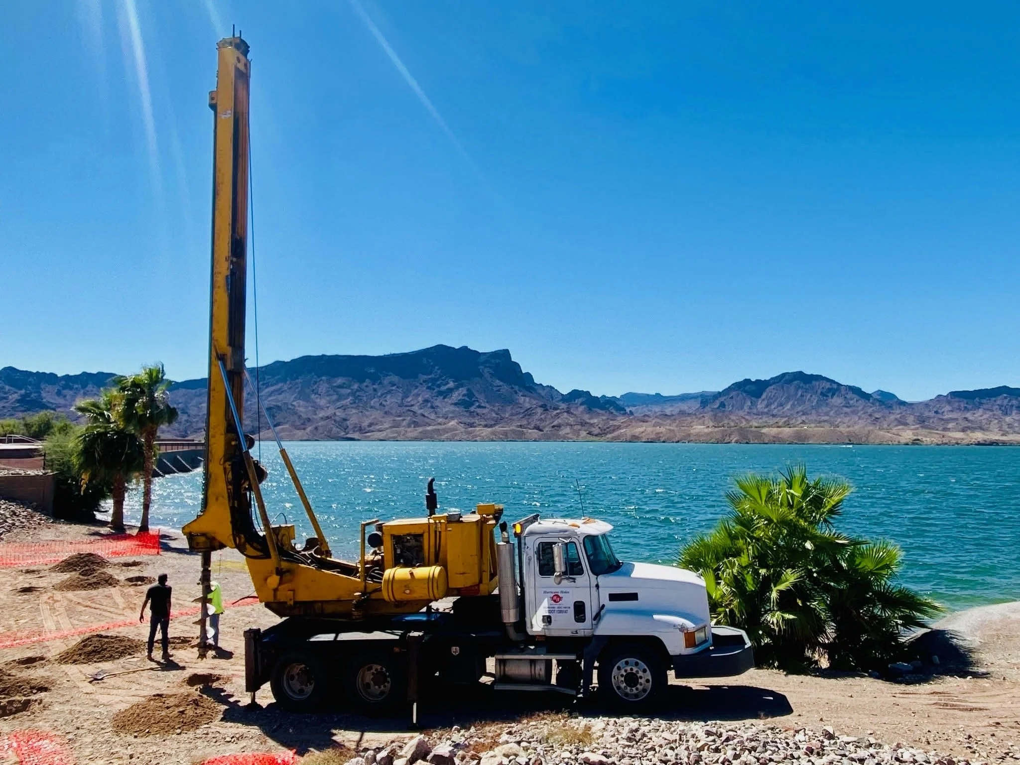 Large drill rig drilling holes next to a lake in Arizona.