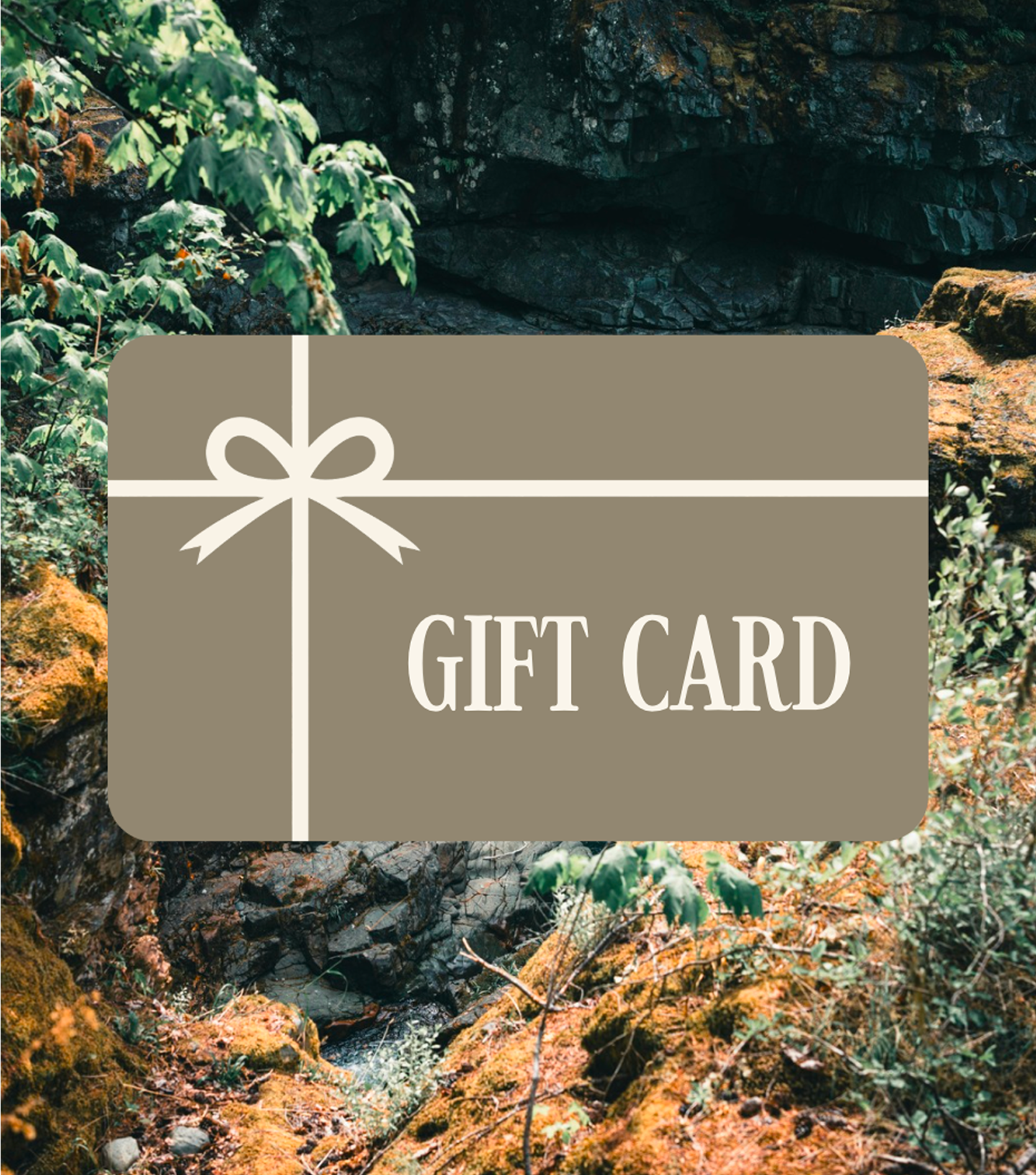 A gift card with a beige background, white ribbon graphic, and the text 'GIFT CARD' in white, overlaid on a photo of a natural outdoor scene with rocks and green plants.