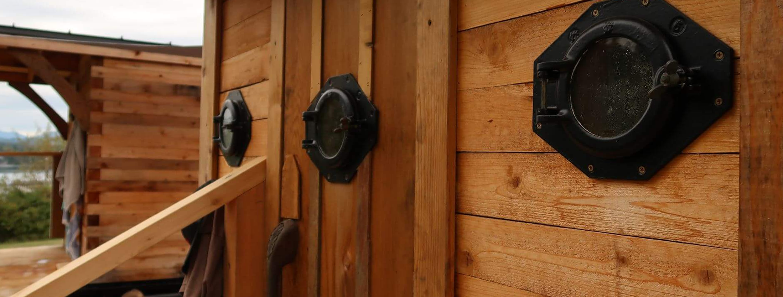 Close-up of three black round lights mounted on a wooden wall.