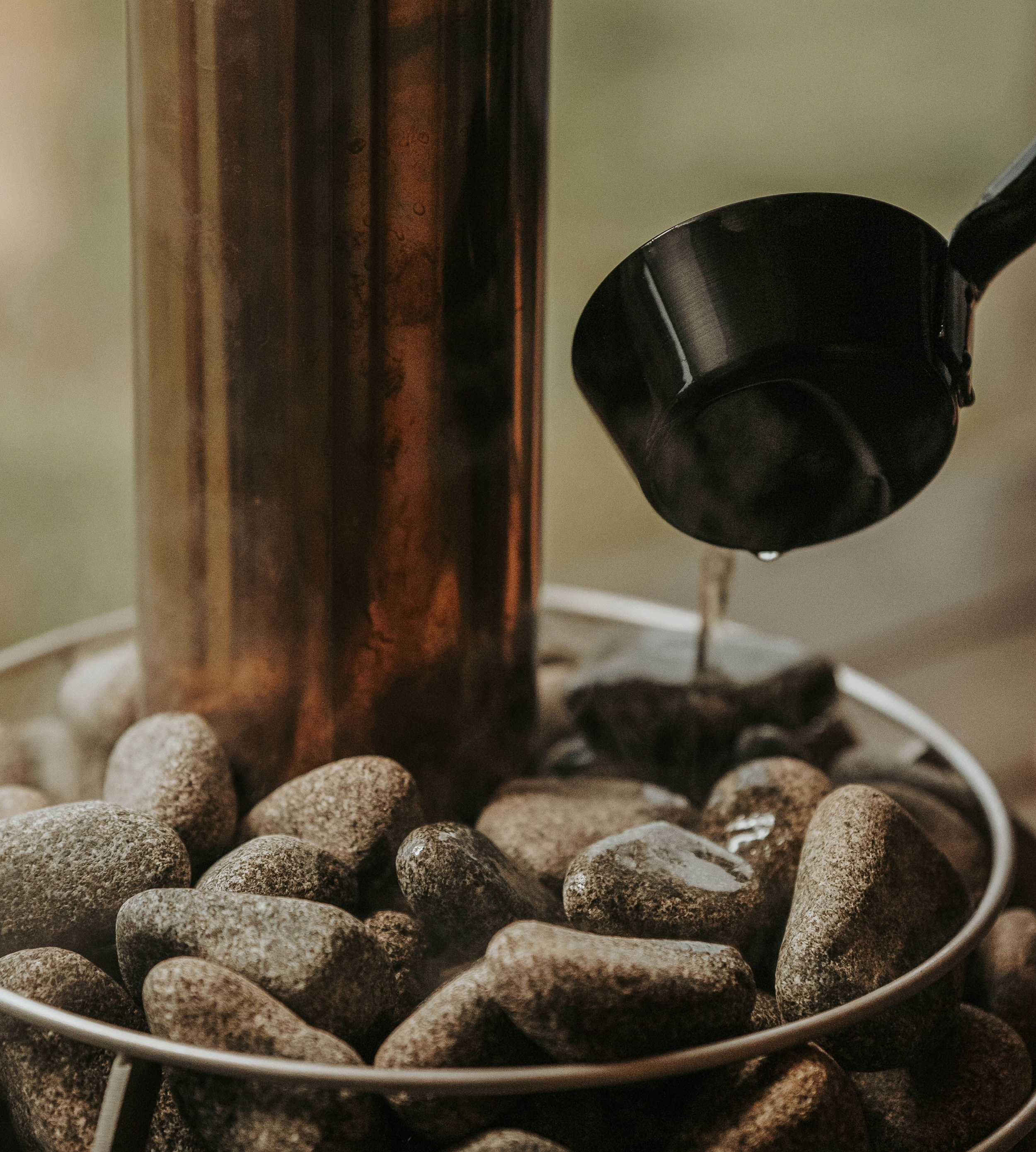 Close-up of a black electric kettle, with a wooden table and small round rocks in the background.